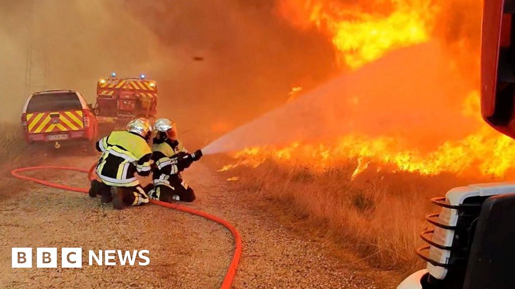 Firefighters work as flames and smoke rise during a wildfire, amid drought conditions following a heatwave and water