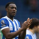 Danny Welbeck, wearing a blue and white striped Brighton shirt, applauds