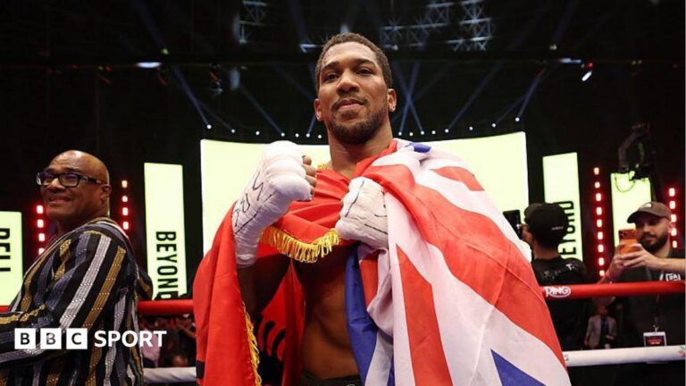 Anthony Joshua celebrates with the Union Jack draped over him
