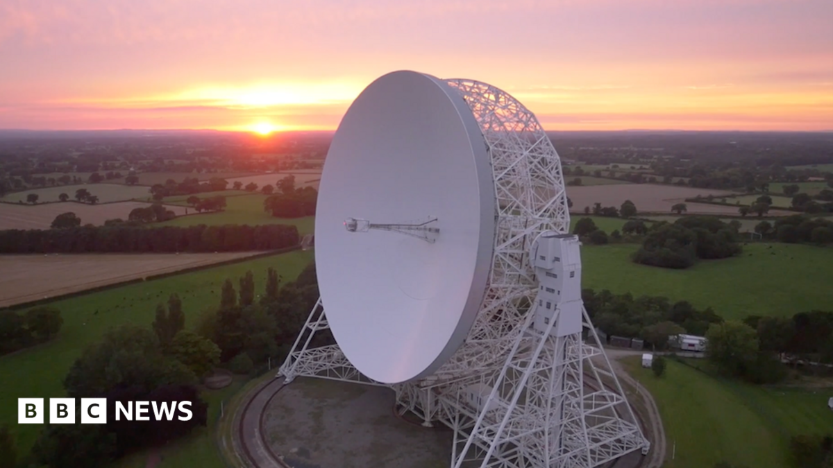 An aerial view at sunrise of the Lovell telescope at Jodrell Bank. Its huge white dish, taller than a house, is tilted