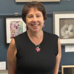 Dr Nicola Fox is stood, smiling, with a gallery of art behind her