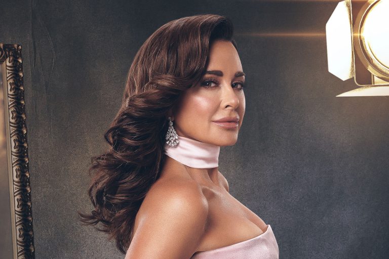 wearing a gown in front of a gray backdrop and spotlight
