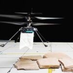 A tiny helicopter drone has a small white cape