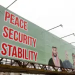 A green billboard, reading 'Peace, Security, Stability'