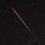 a streak of light crosses through the night sky