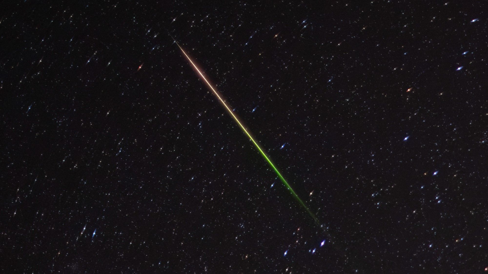 a streak of light crosses through the night sky