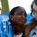 Ethiopia's Tigst Assefa (C) is helped off the track after crossing the finish line to win the women's race of 52nd Berlin