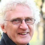 Terry Denton smiles at the camera wearing glasses and smiling