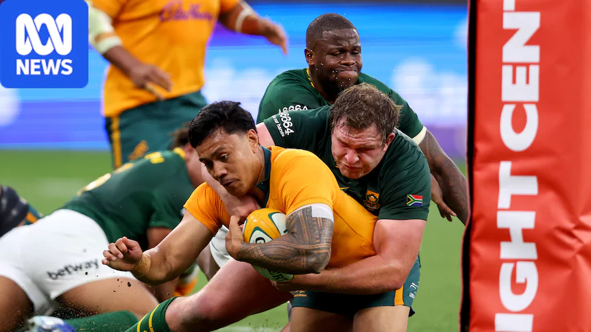 A rugby player in yellow scores a try while being tackled by players in green