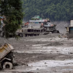 A wide shot shows trucks and houses sinking into mud