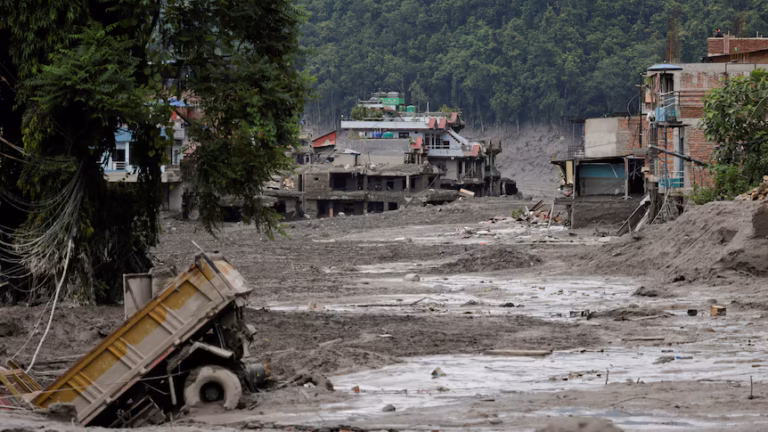 A wide shot shows trucks and houses sinking into mud