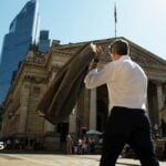 A commuter carries his jacket on a sunny day in the City of London