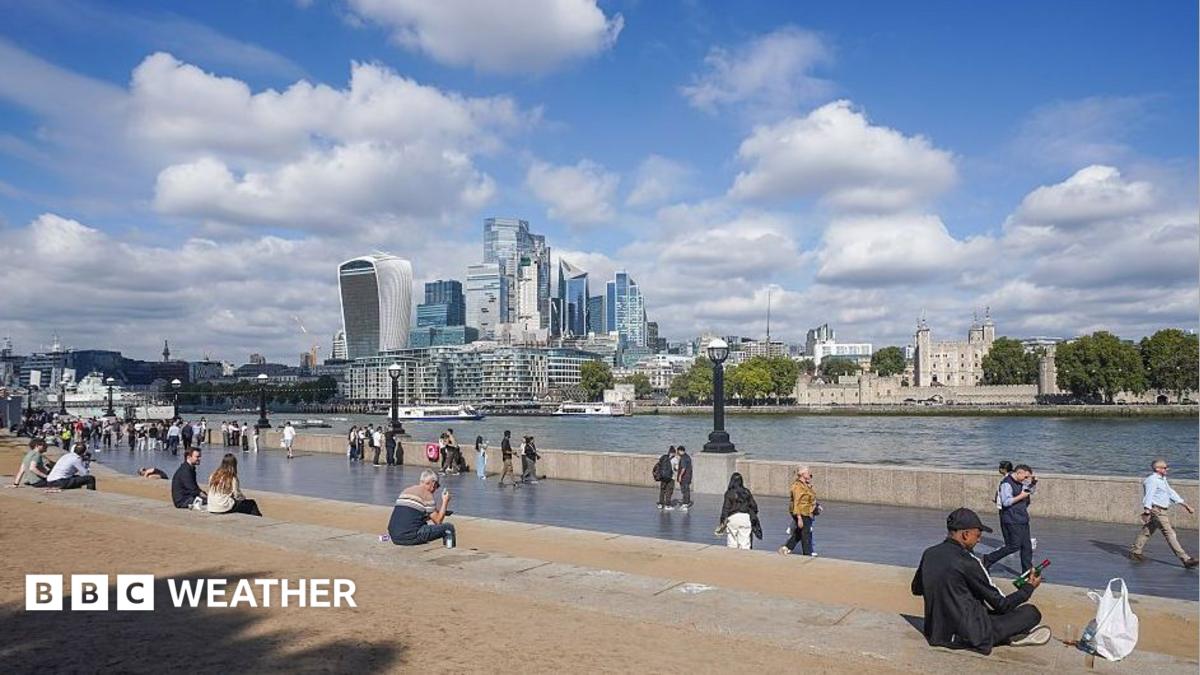 People sit in the autumn sunshine by the London Riverside in London