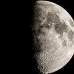 The moon is photographed with its right side lit by sunlight in a black night sky