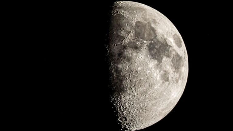 The moon is photographed with its right side lit by sunlight in a black night sky