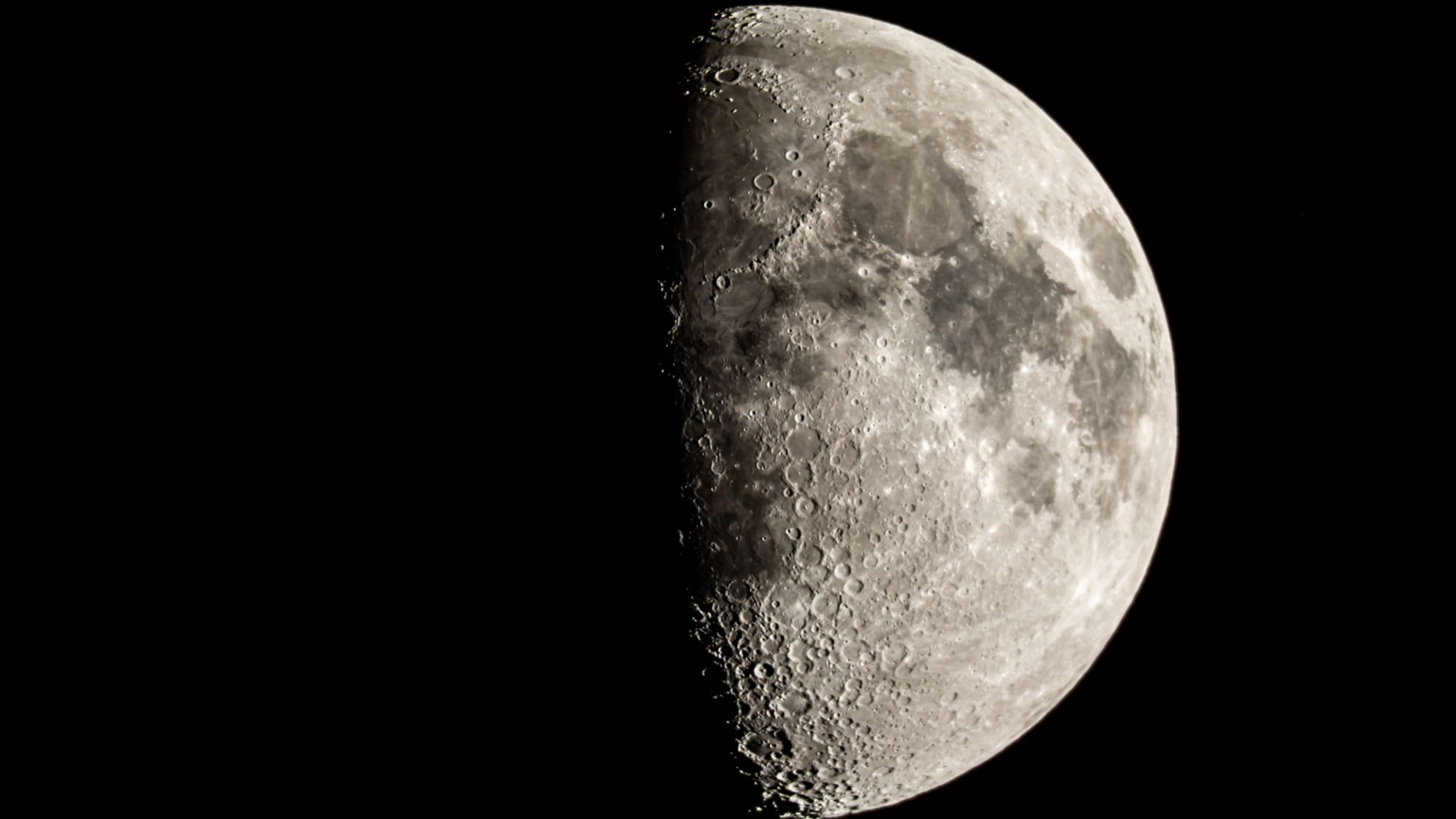 The moon is photographed with its right side lit by sunlight in a black night sky