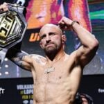 Alexander Volkanovski raises his UFC featherweight title after a news conference