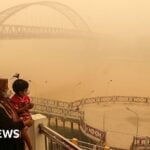 Mother and child wearing face masks look on from a bridge as thick haze from forest and land fires in the region in
