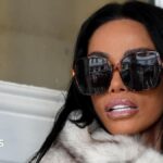 A close up of Katie Price arriving at Lewes Crown Court, she is wearing large dark sunglasses and looking over her shoulder