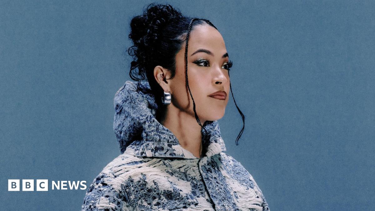 Jazzy, pictured wearing a blue and white jacket embroidered with country scenes. The 30-year-old has her dark hair tied back