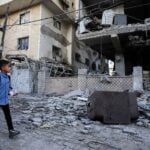 Palestinian children walk past the site of an Israeli strike on an apartment building in Gaza City, October 3, 2026
