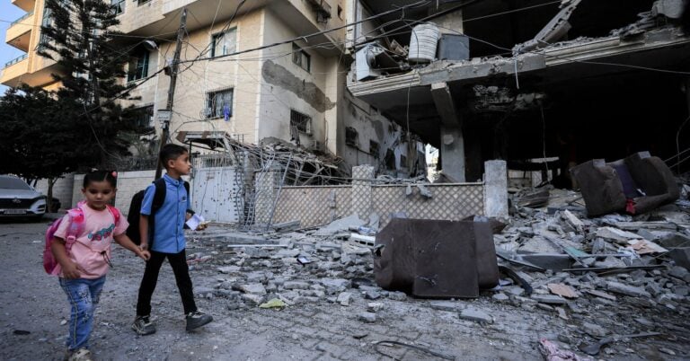 Palestinian children walk past the site of an Israeli strike on an apartment building in Gaza City, October 3, 2026