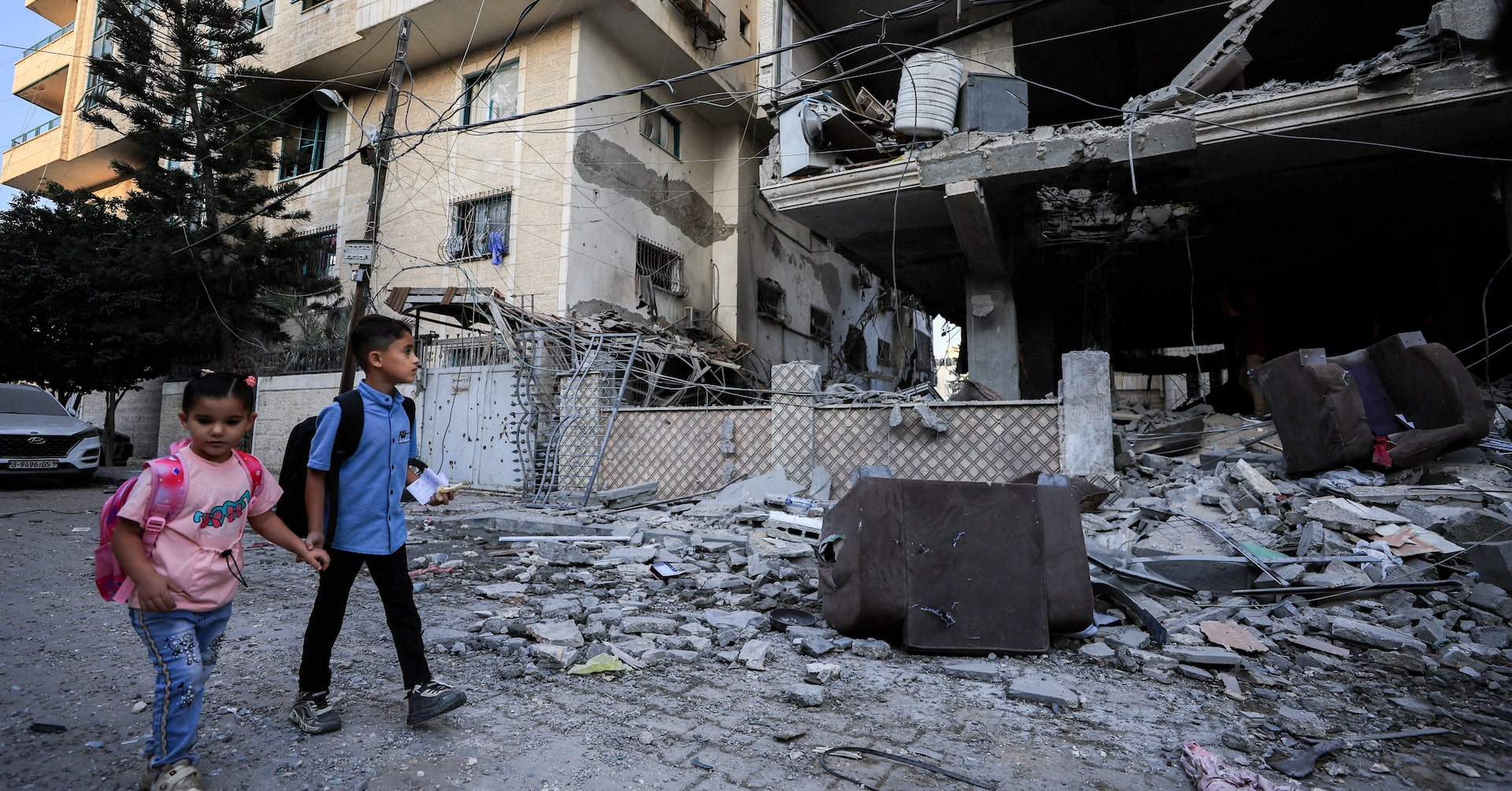 Palestinian children walk past the site of an Israeli strike on an apartment building in Gaza City, October 3, 2026