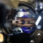 A close up of a laser table with lasers and mirrors on it