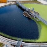 Overhead shot of a sewage treatment works, part of which is covered in what appears to be green algae