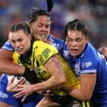 Female rugby league player trying to break free from two defenders