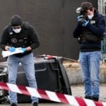 Police officers look at evidences on a site of a petrol station where a man opened fire from his car, killing one person and