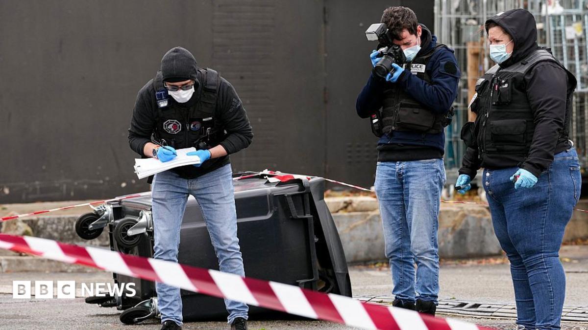 Police officers look at evidences on a site of a petrol station where a man opened fire from his car, killing one person and