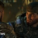 Gears of War character Marcus Fenix wears a bandanna and heavy futuristic armour. The CGI character has a cropped beard and