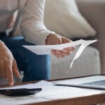 person taking note of expenses and working on calculator