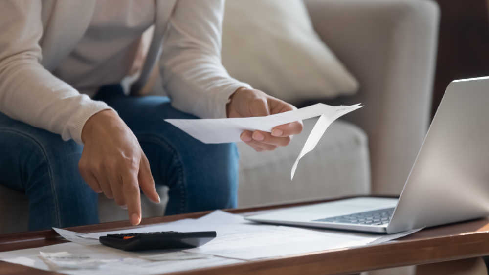 person taking note of expenses and working on calculator