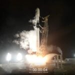 a black and white rocket launches into a night sky