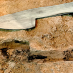 Image of a stone block with the imprint of a device with a blade and handle, with a model of a wooden version of the object