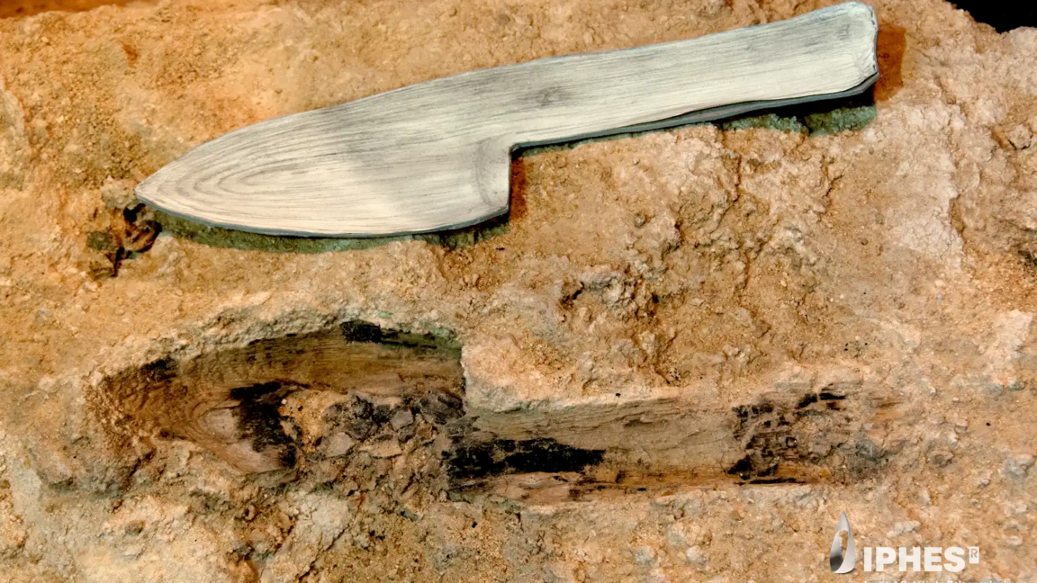 Image of a stone block with the imprint of a device with a blade and handle, with a model of a wooden version of the object