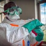 A health worker wearing personal protective equipment, including goggles, a face mask, a protective suit and gloves