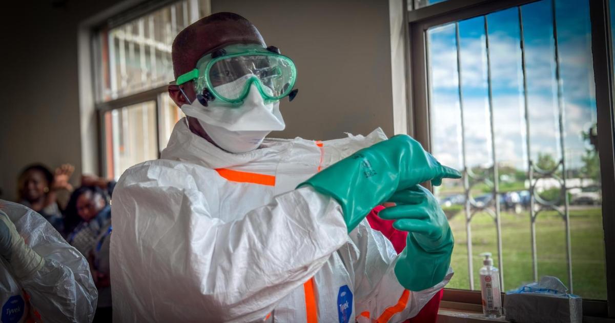 A health worker wearing personal protective equipment, including goggles, a face mask, a protective suit and gloves