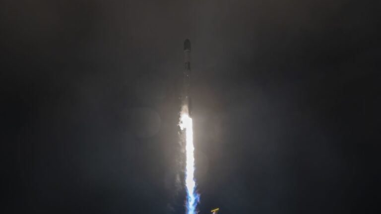 A white rocket blasts off in the dark of night