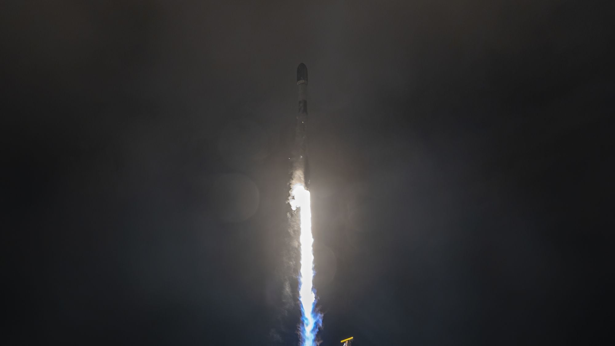 A white rocket blasts off in the dark of night